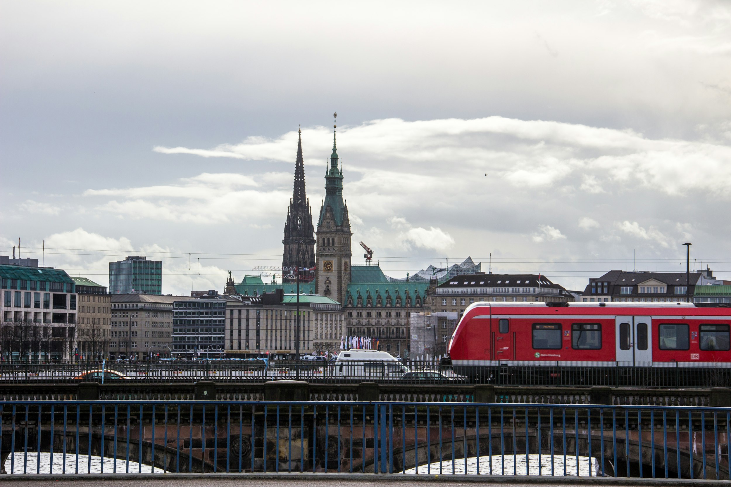 red and white train on rail bridge near city buildings during daytime
