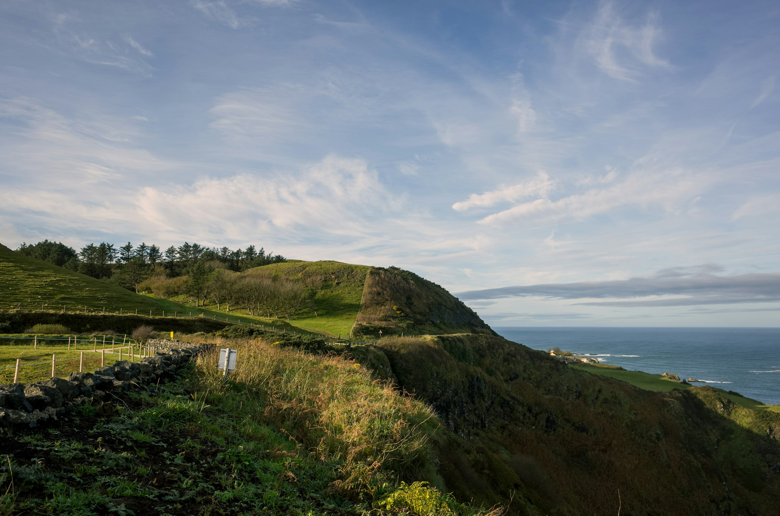 a scenic view of a grassy hill with a body of water in the background