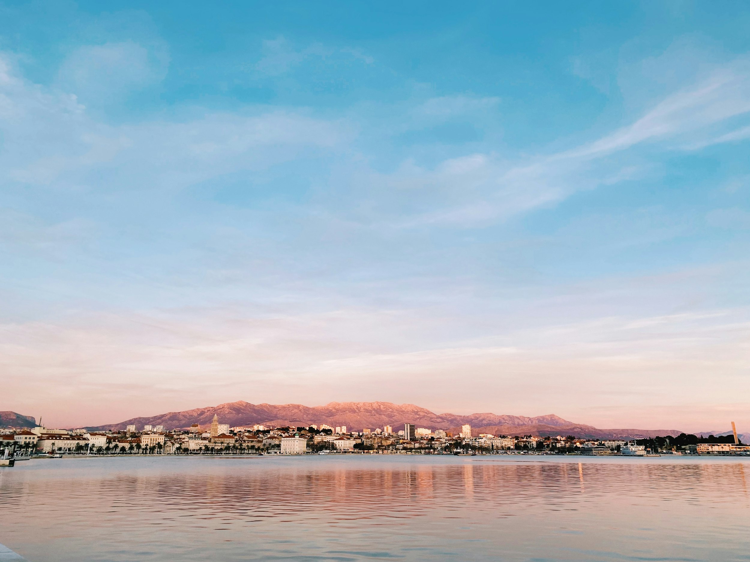 body of water near mountain under blue sky during daytime