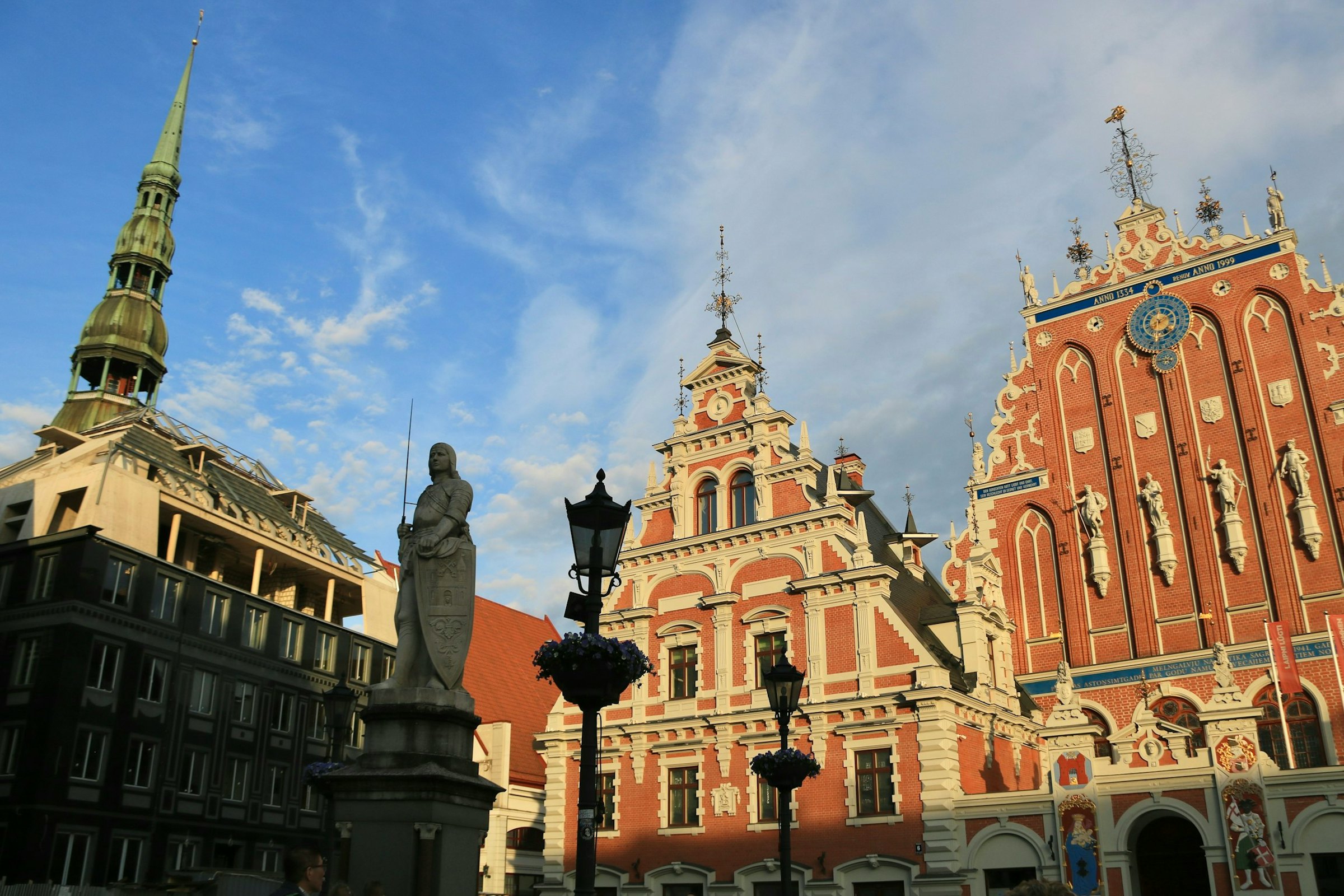 Ornate red-brick House of the Blackheads with clock tower and church spire, Riga, Latvia