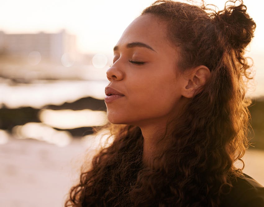 Woman with brown curly hair standing outside