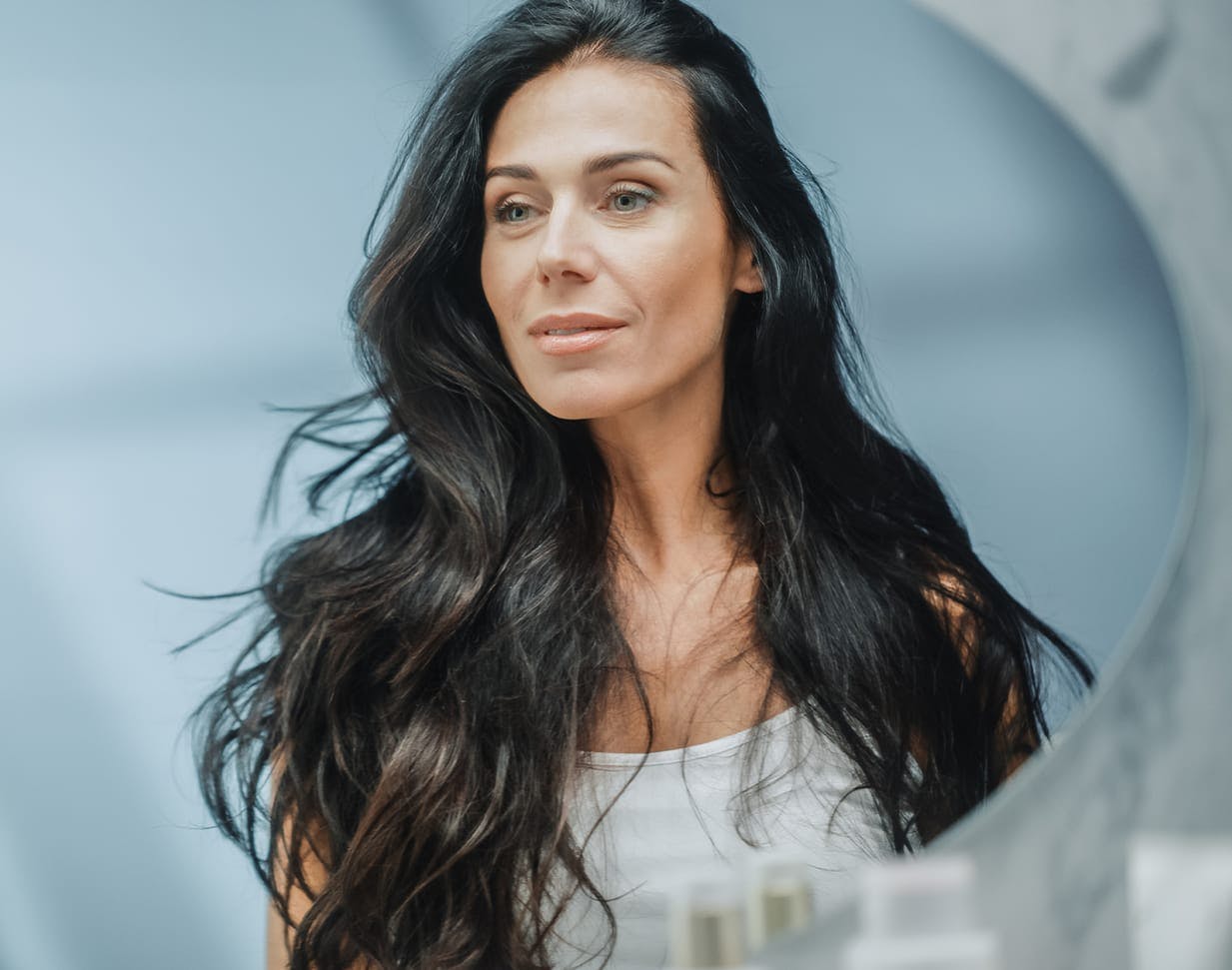 Dark-haired woman looking into the mirror