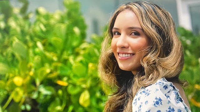 Woman smiling outside standing in front of a bush