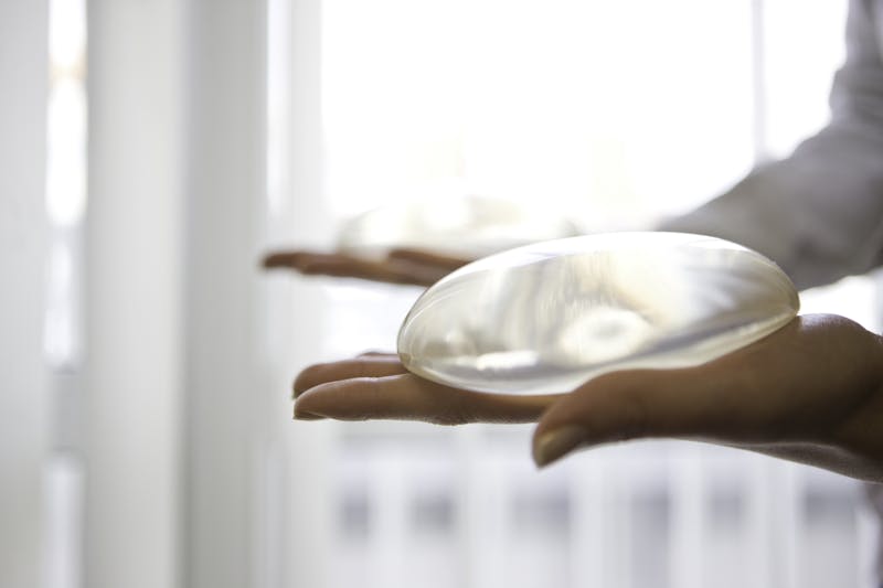 someone holding a breast implant in their hand near a window