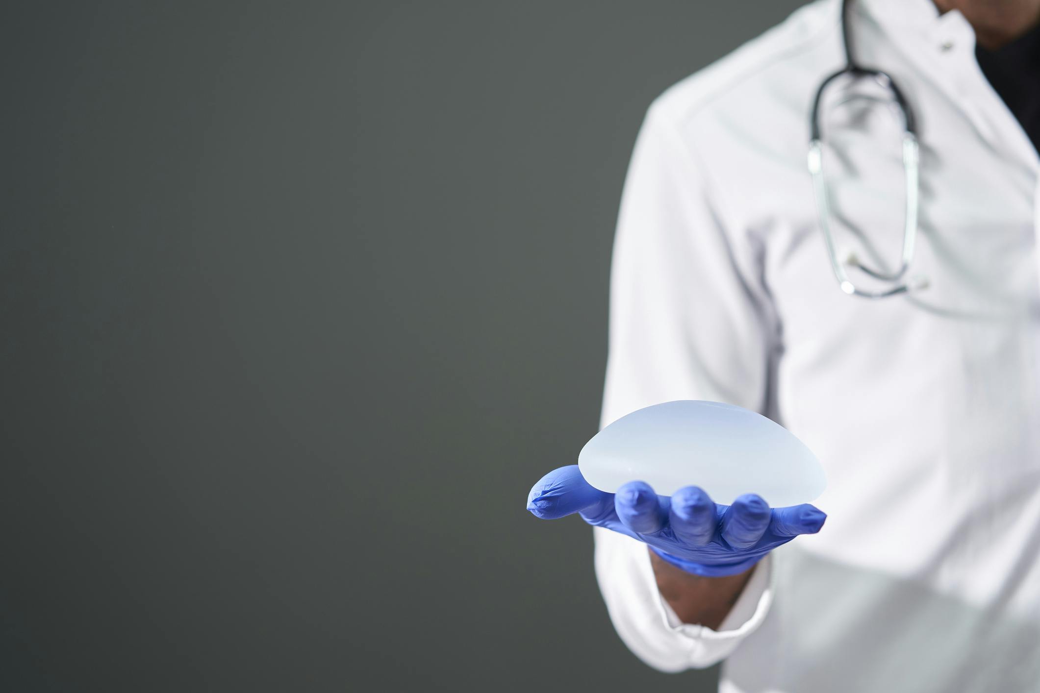 male doctor holding breast implant