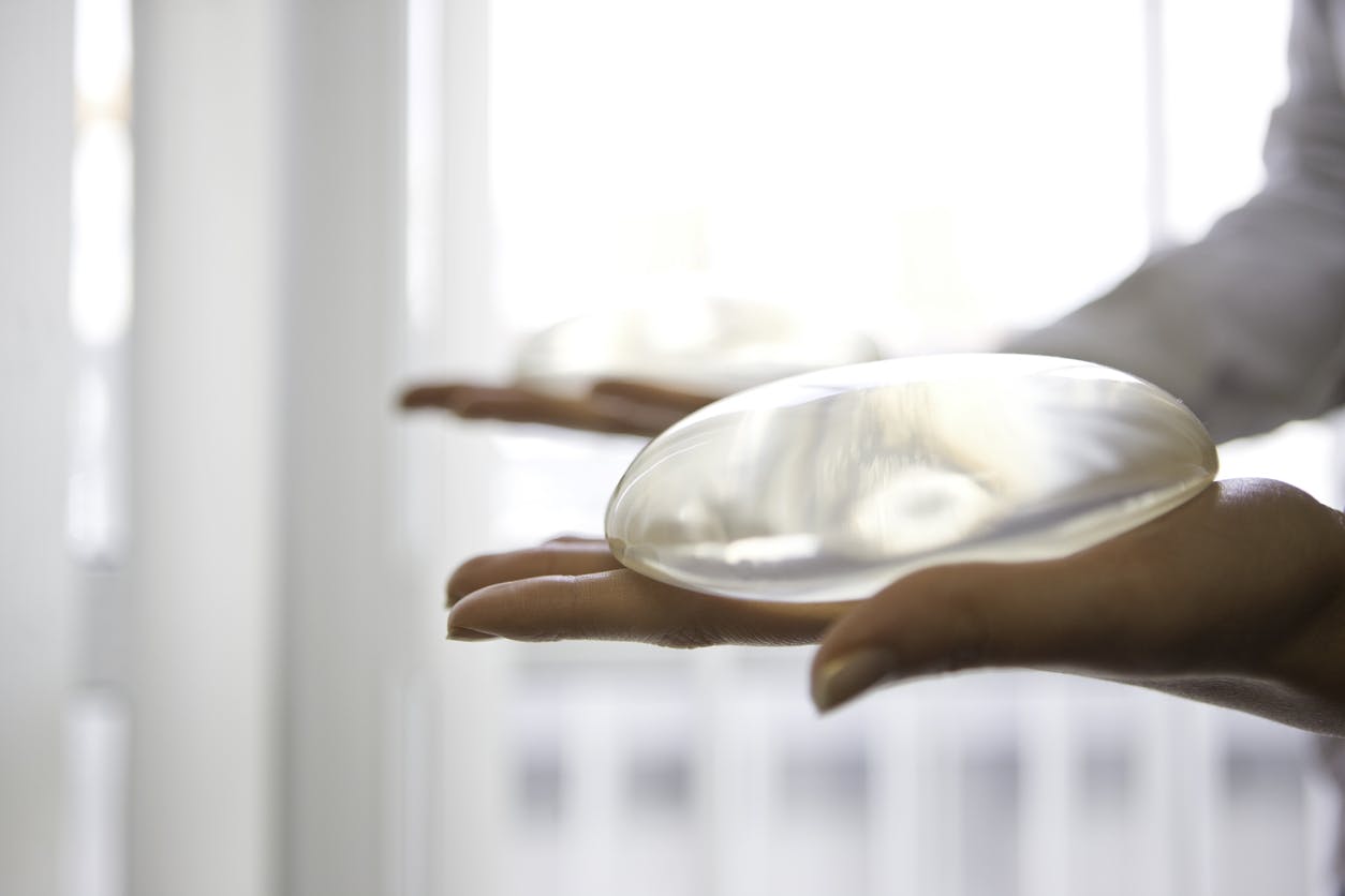Woman holding two breast implants