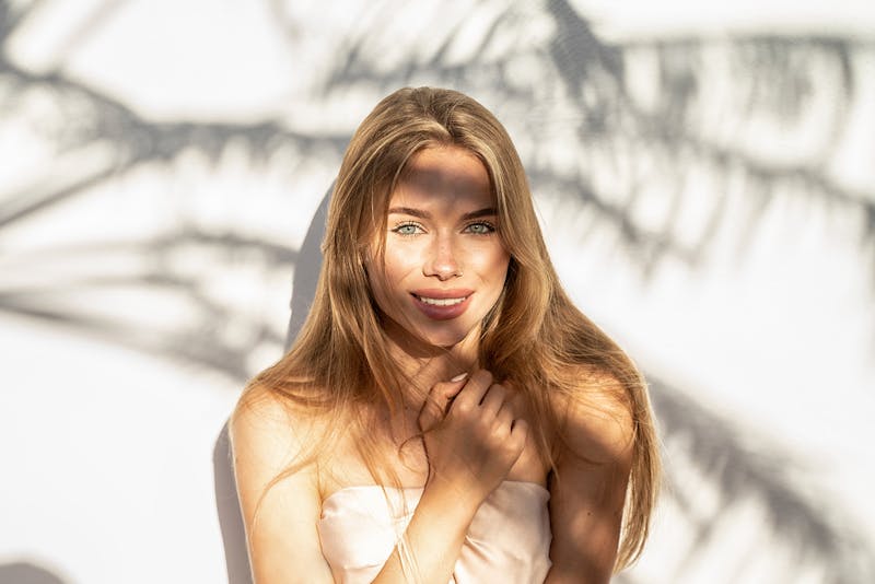 Beautiful blonde woman posing in a palm tree's shadow
