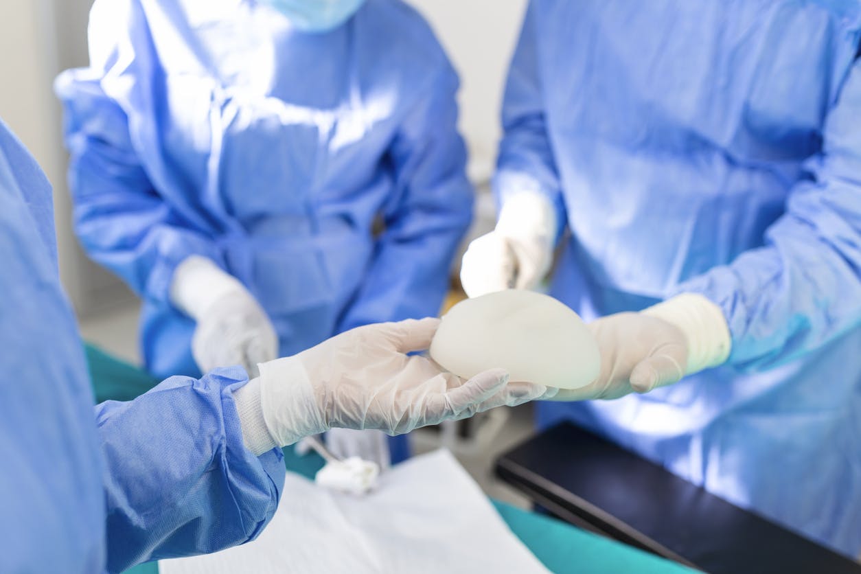 surgeons holding breast implant