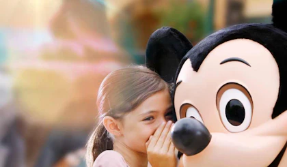 Young girl whispering in Mickey Mouse's ear at Disneyland Paris