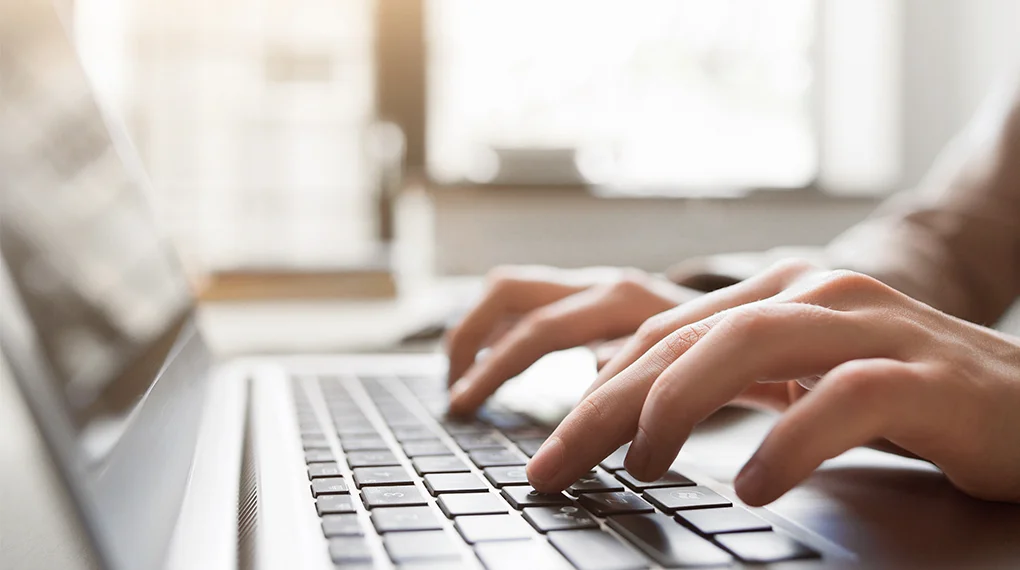 A person typing at a laptop