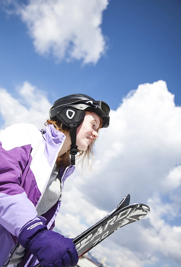 A young skiier carrying their kit