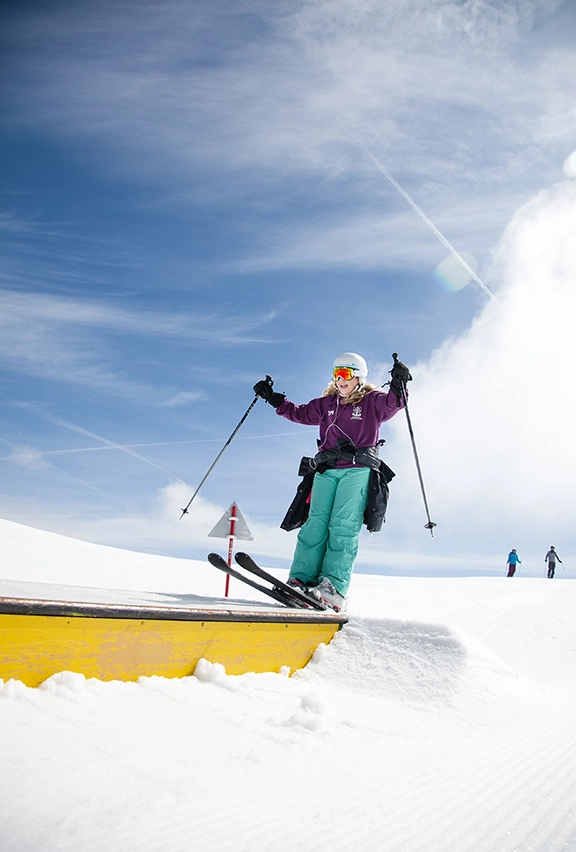 A girl sliding along a box on her skis