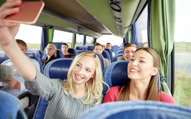 Two girls take a selfie whilst on a group coach