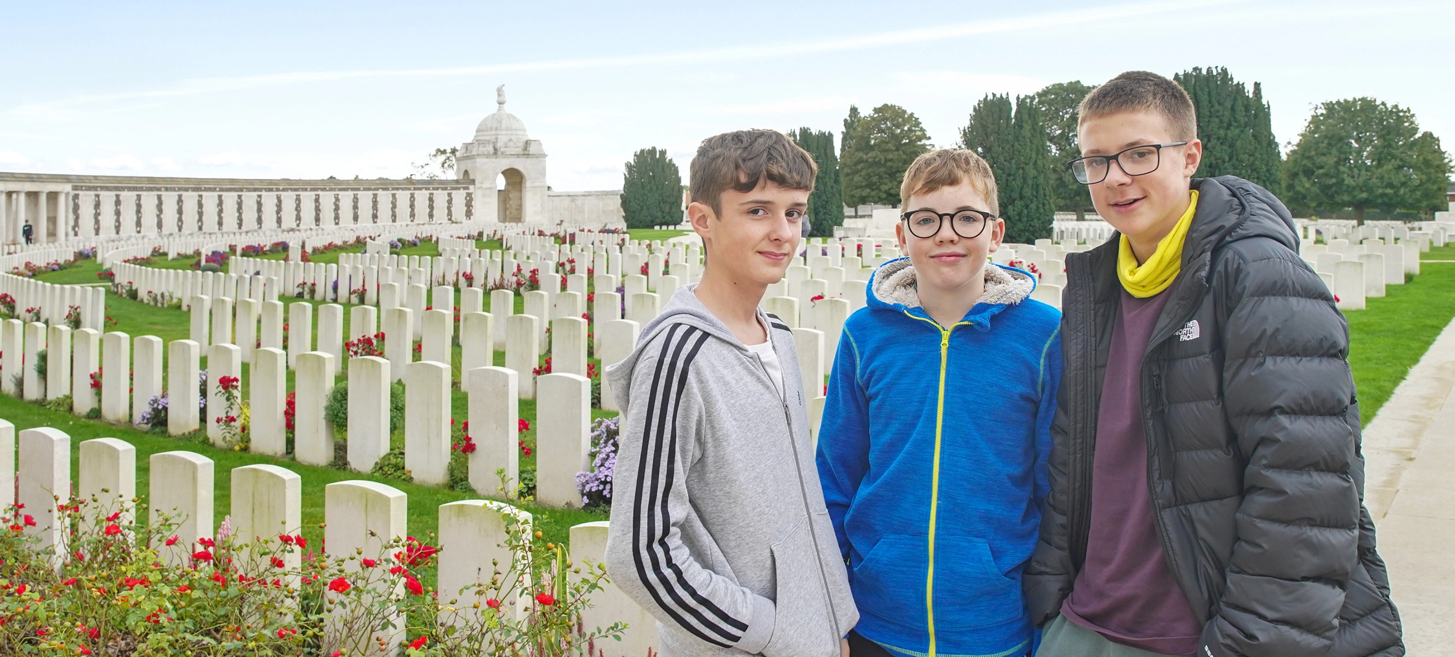 3 students stand in Tyne Cot Cemetary, Ypres