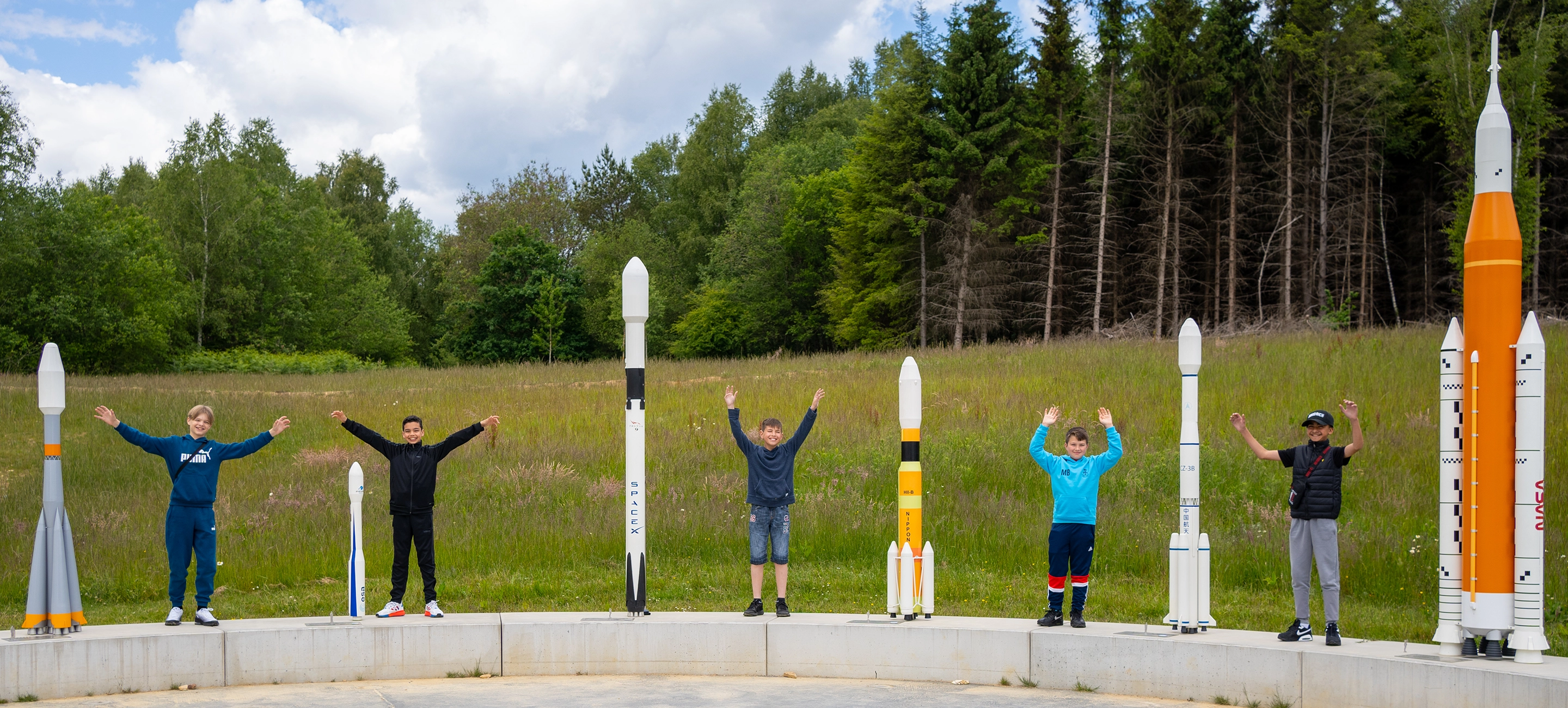 5 students stand between model rockets at the Kennedy Space Centre