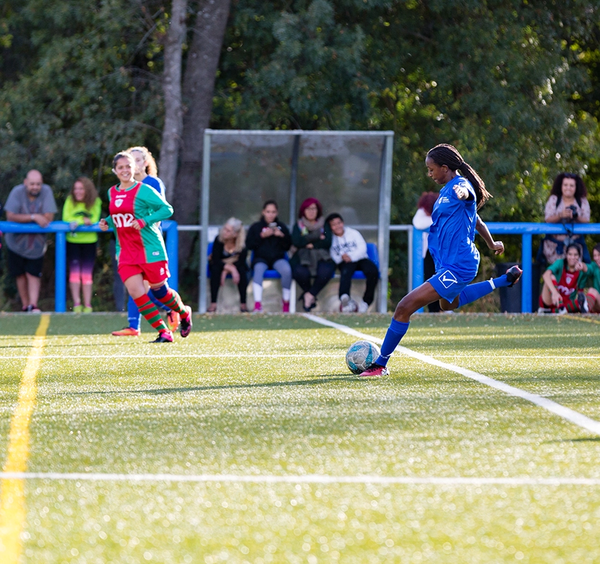 A girl in blue kicking a football