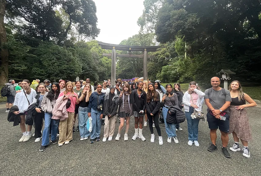 A group of students stand in front of a torii in Japan