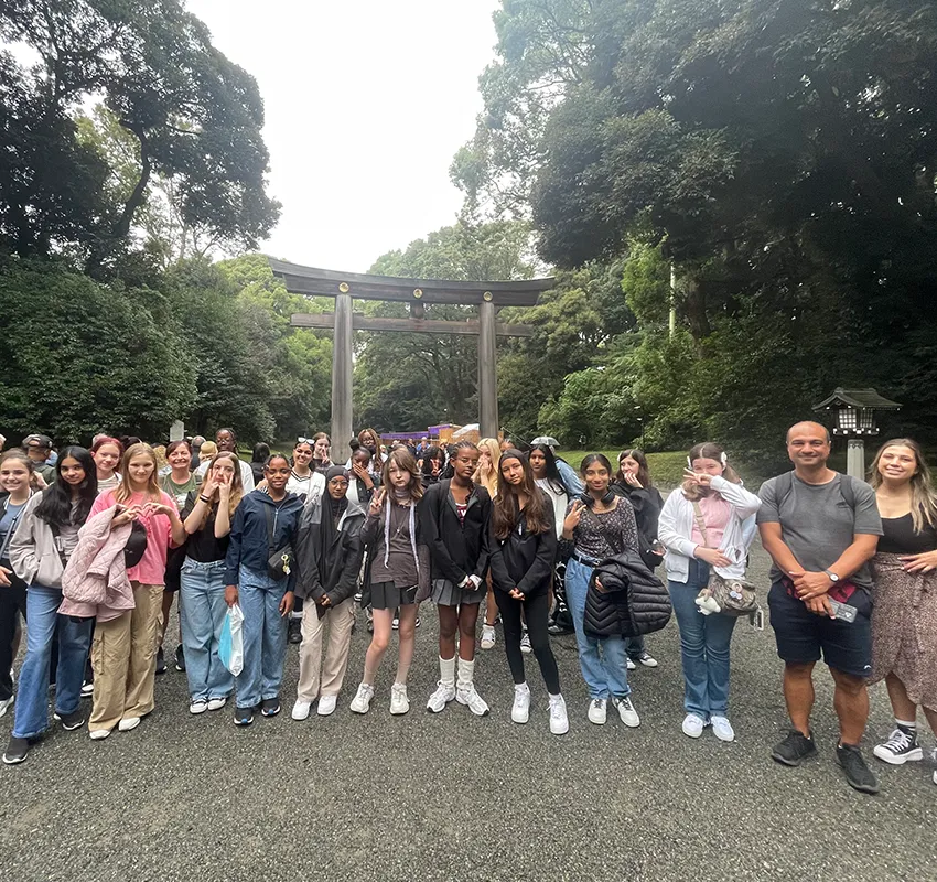 A group of students stand in front of a torii in Japan
