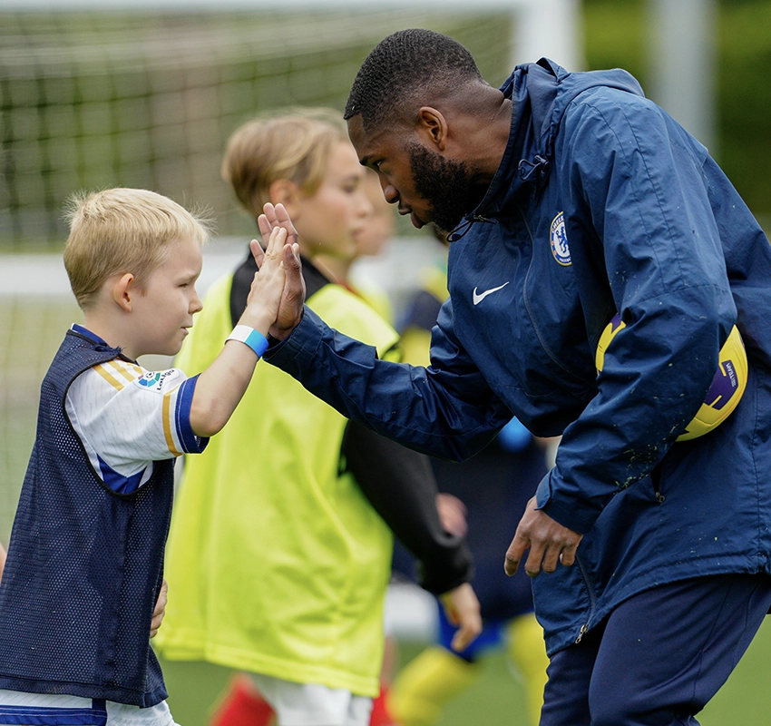 Chelsea football player high fiving a primary school student