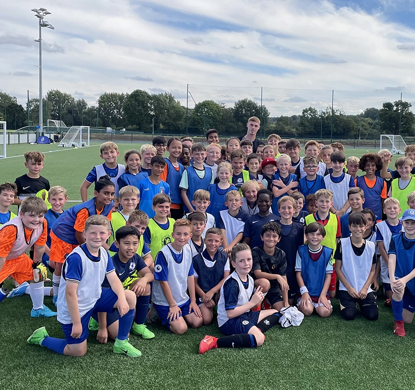 A group of primary school students in football kits gathered for a group photo