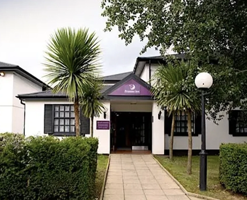 Hotel entrance with palm trees and hedges lining the footpath