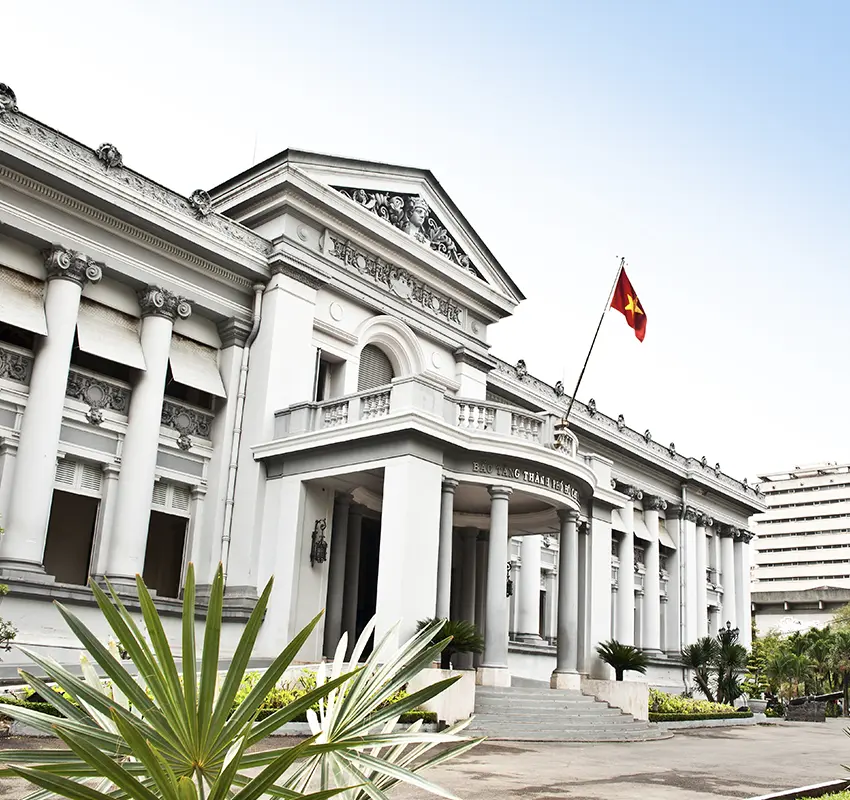A white, classical-style museum building with Vietnam flag on balcony