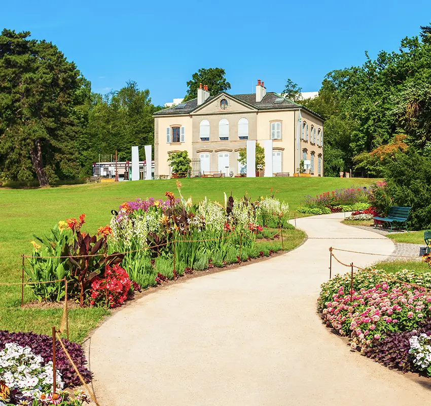 Colourful flowers alongside a garden path, with a traditional garden conservatory in the background