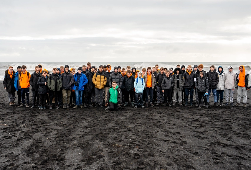 A School Group on Reynisfjara Beach, Iceland A large school group, in colourful hoodies, stand on the black sand beach of Reynisfjara in Iceland