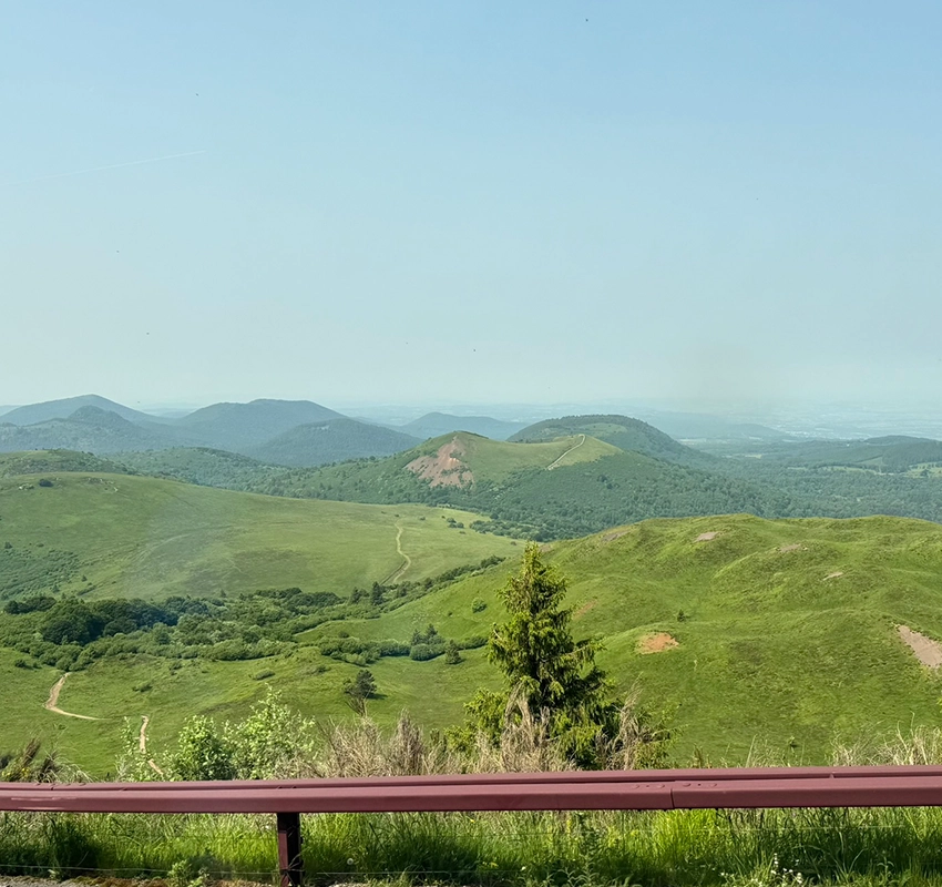 Green hills stretching far into the background, under a misty blue sky