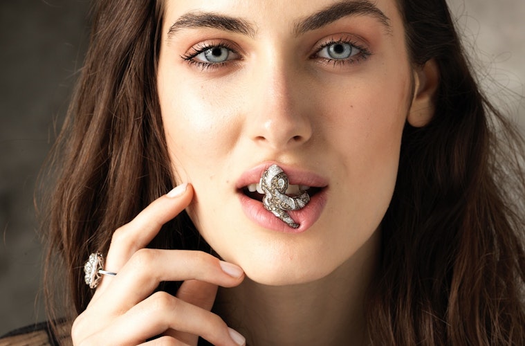 Close-up model holding a precious jewel with her mouth