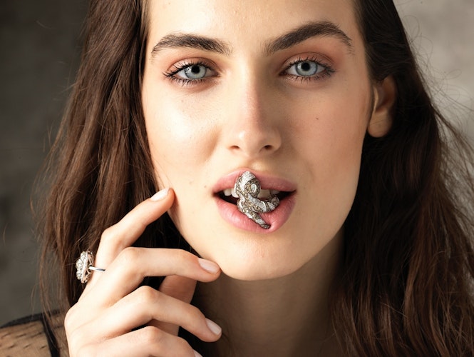 Close-up model holding a precious jewel with her mouth