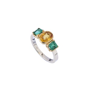 anello con zaffiro giallo e smeraldi su sfondo bianco