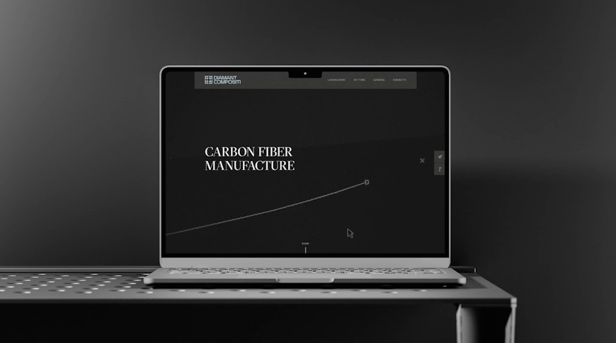 Un laptop con un sito web aperto sullo schermo mostra Carbon Fiber Manufacture in testo bianco su uno sfondo scuro. Il laptop è appoggiato su una superficie metallica perforata contro una parete scura.