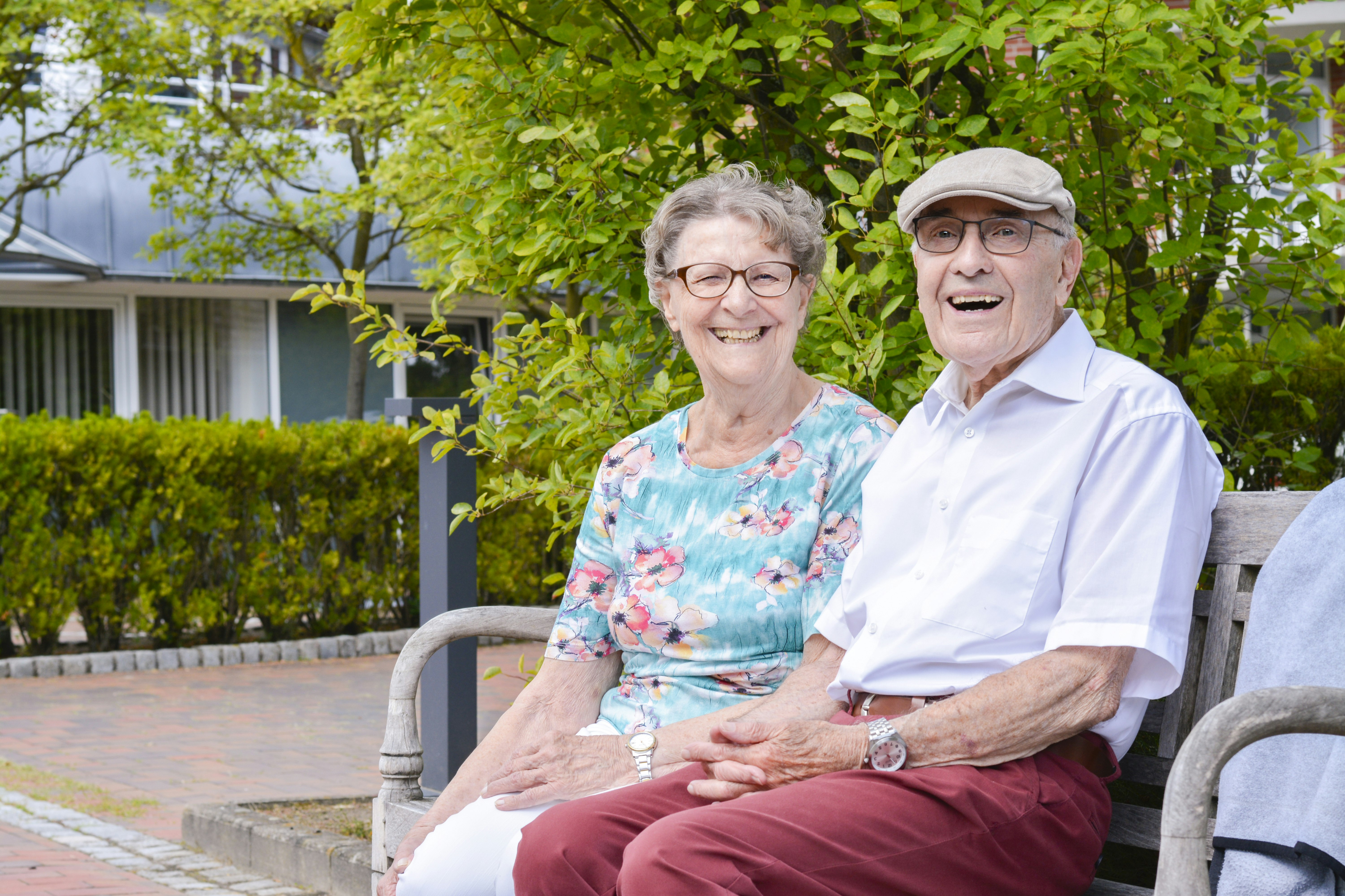 älteres Ehepaar, lachend auf einer Bank