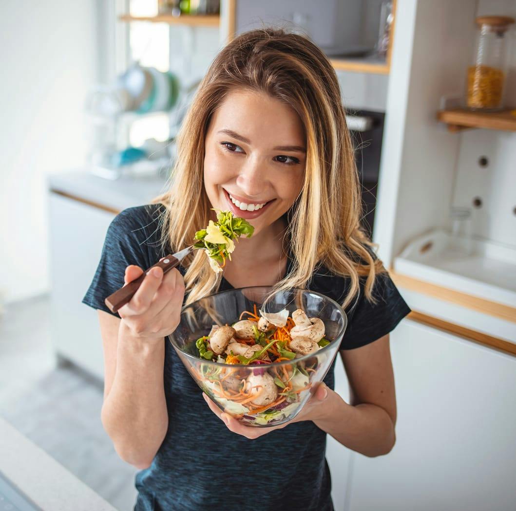 Woman smiling eating a healthy salad.