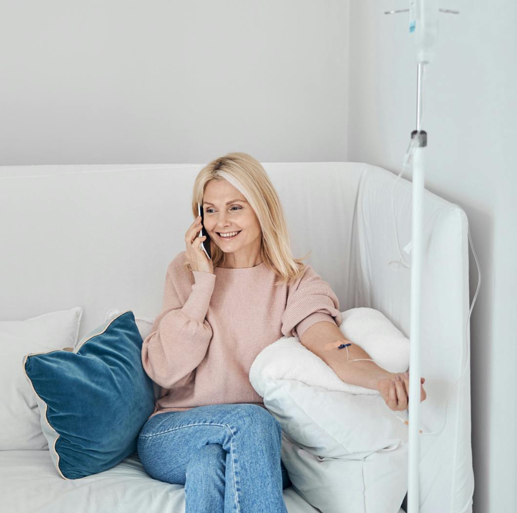 Woman sitting, talking on the phone, getting an IV
