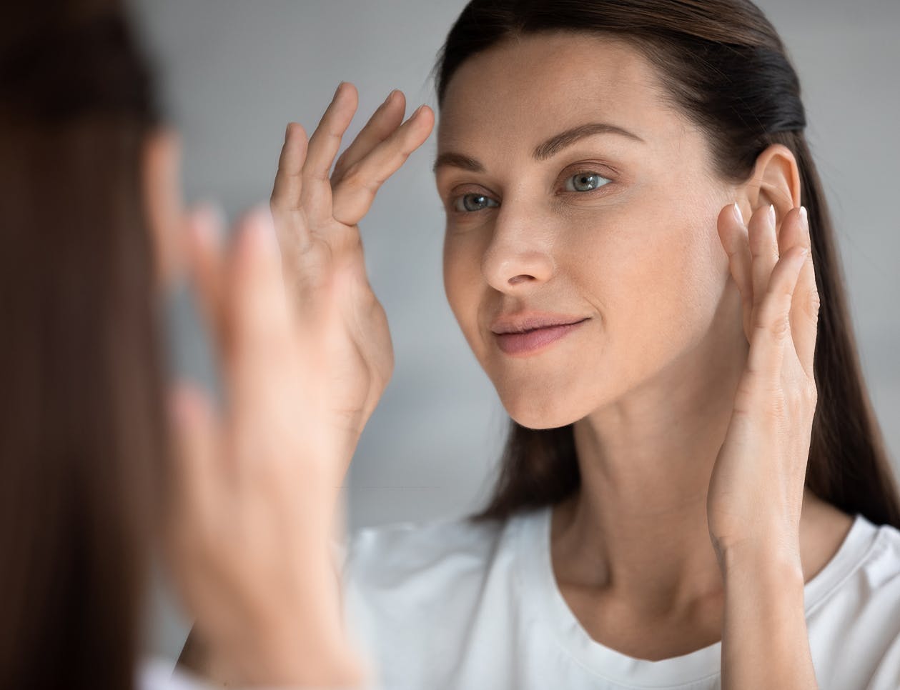 Woman looking at her face in a mirror