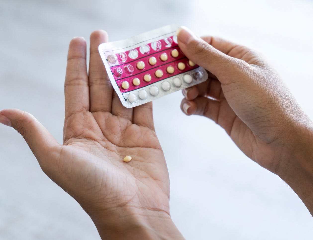 Hands taking a pill out of a pill case