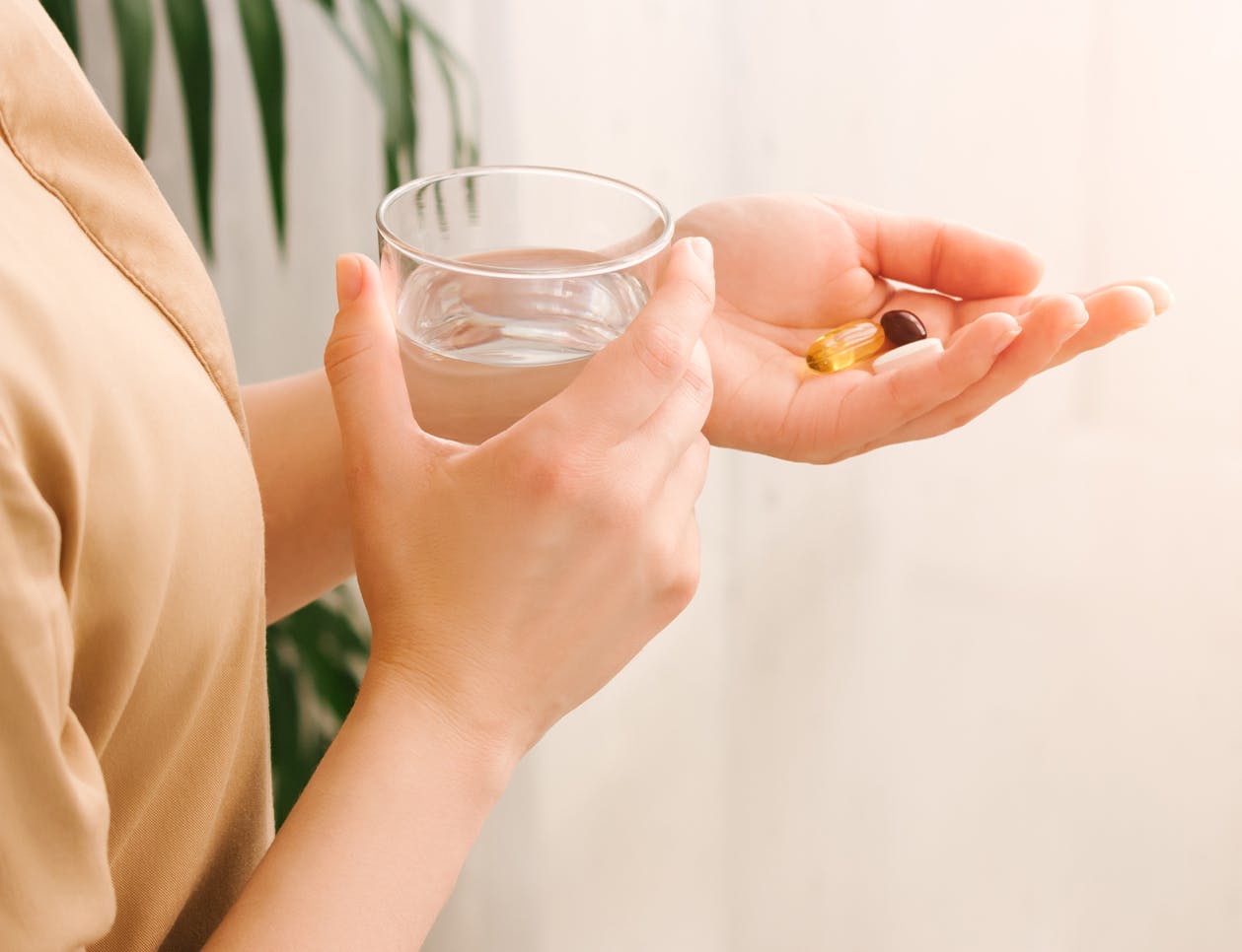 Woman with three pills in her hand and a glass of water