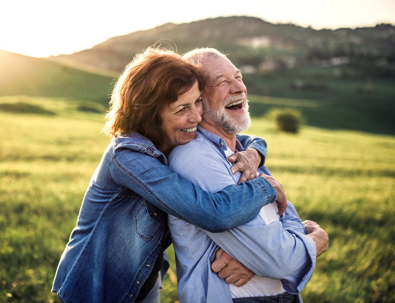 Woman hugging a man from behind while outside in a field