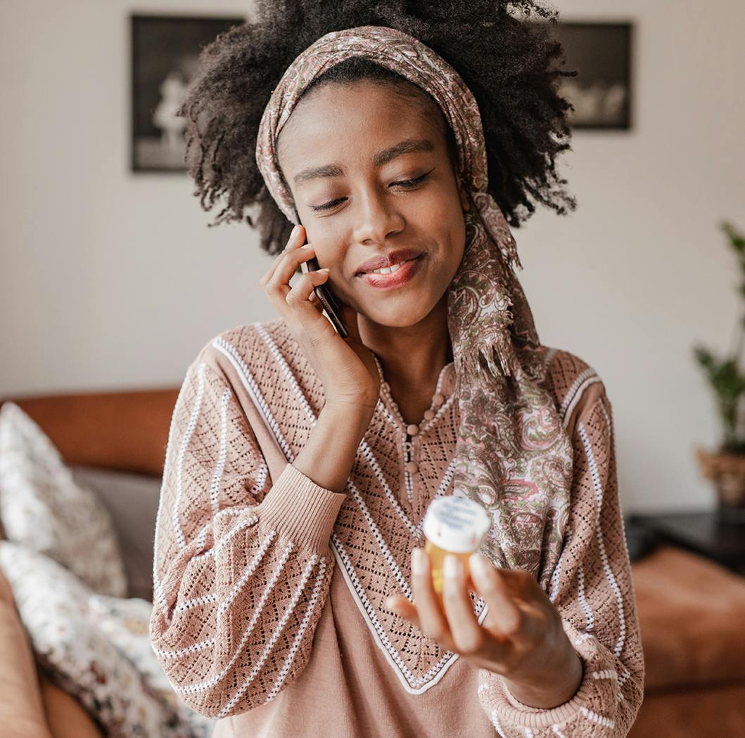 Woman talking on the phone with a bottle of pills in her hand