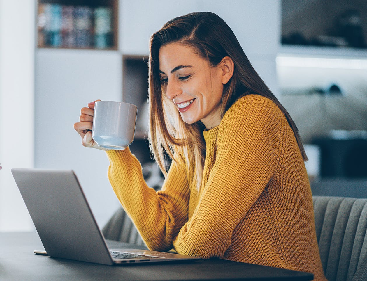 Woman with a coffee mug in her hand looking at her computer