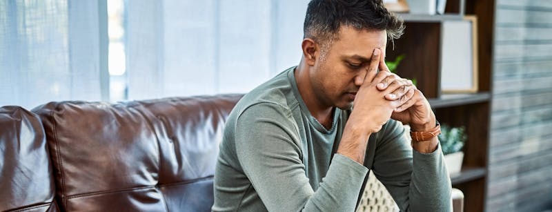 Man sitting down with face in hands.