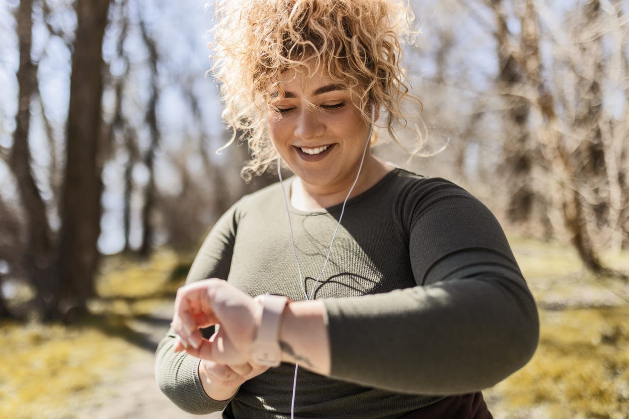 Woman smiling and looking at wrist pedometer