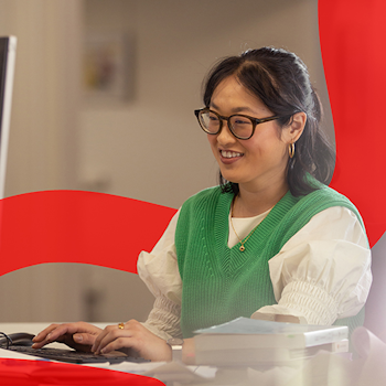 Women in green vest and glasses typing on computer.