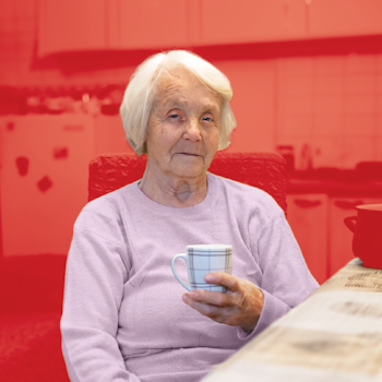 Elderly woman holding cup of tea on red background.