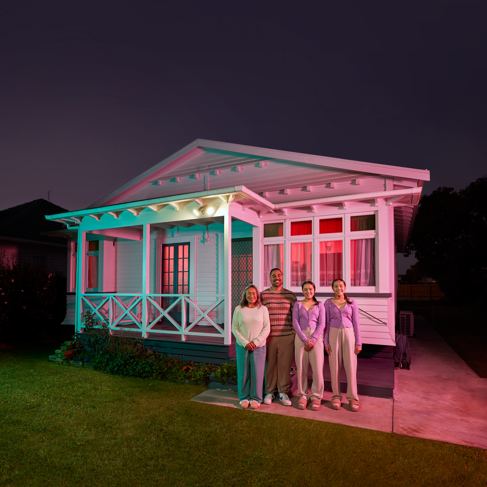 Family standing in front of house at night.