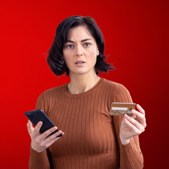Photo of woman holding phone and credit card on red background.