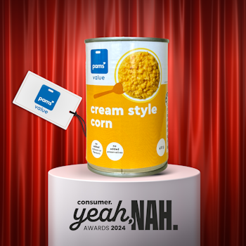 Can of Pams cream style corn on plinth in front of red curtain.