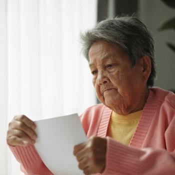 Older woman with short grey hair reading a bill.